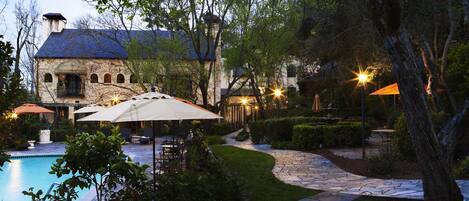 Un sendero de piedra que lleva a una zona de piscina con mobiliario exterior y sombrillas.