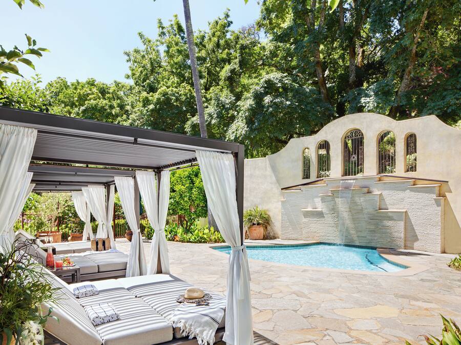 A private pool area with a covered seating area, stone flooring, and a fountain wall.