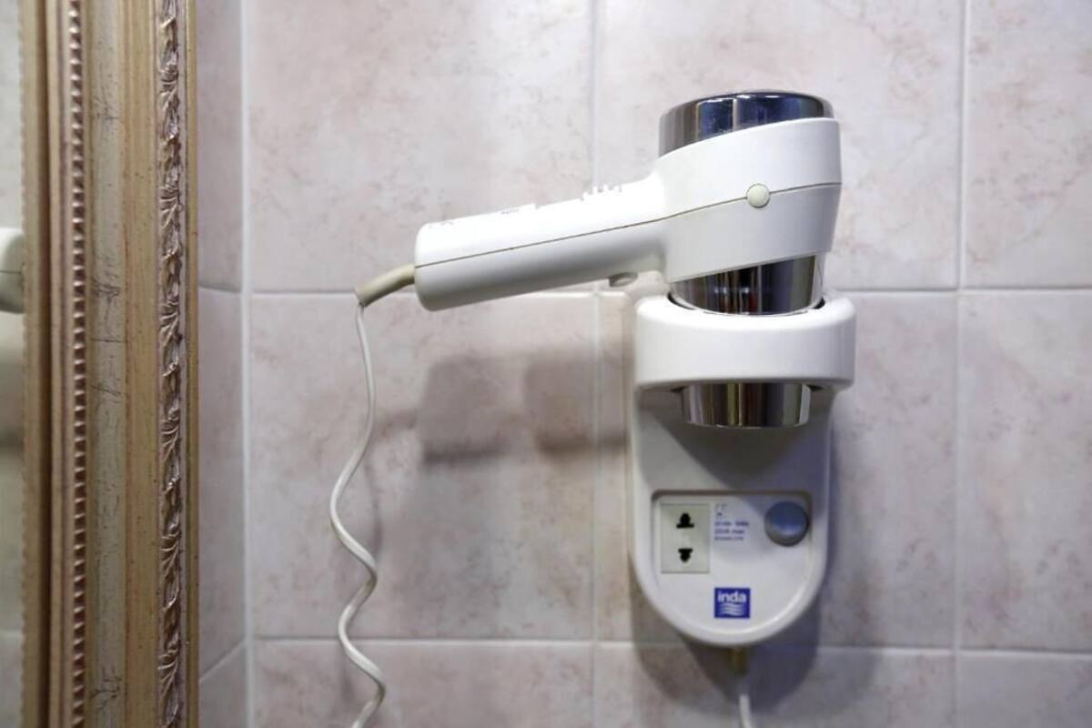 A wall-mounted hair dryer with a control panel, connected to a power outlet.
