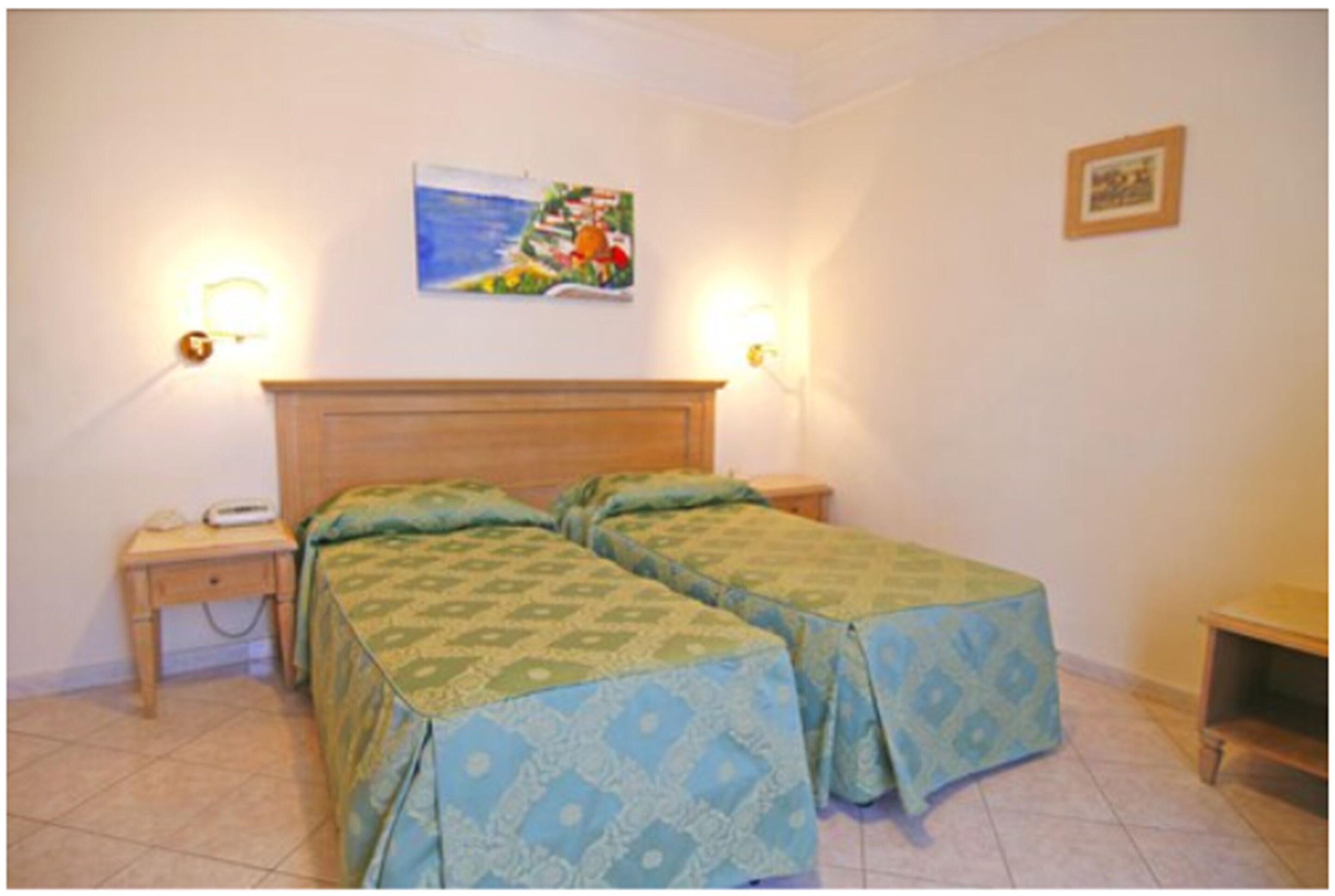 Une chambre avec deux lits, une tête de lit en bois, des lampes de chevet, une petite table et un tableau au mur.