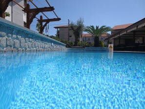 Una piscina al aire libre de temporada, sillones reclinables de piscina