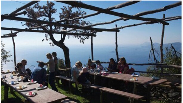 A group of people dining outdoors at wooden tables with a scenic view. - Hotel Due Torri (Agerola)