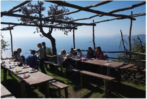 A group of people dining outdoors at wooden tables with a scenic view. - Hotel Due Torri (Agerola)