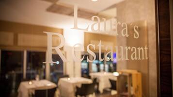 Interior de un restaurante con mesas y sillas, y un letrero que dice 'Laura's Restaurant'.