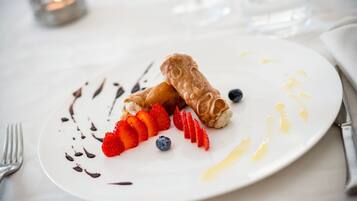 Ein Teller mit Dessert, Erdbeeren und Blaubeeren, dazu Gabel und Messer.