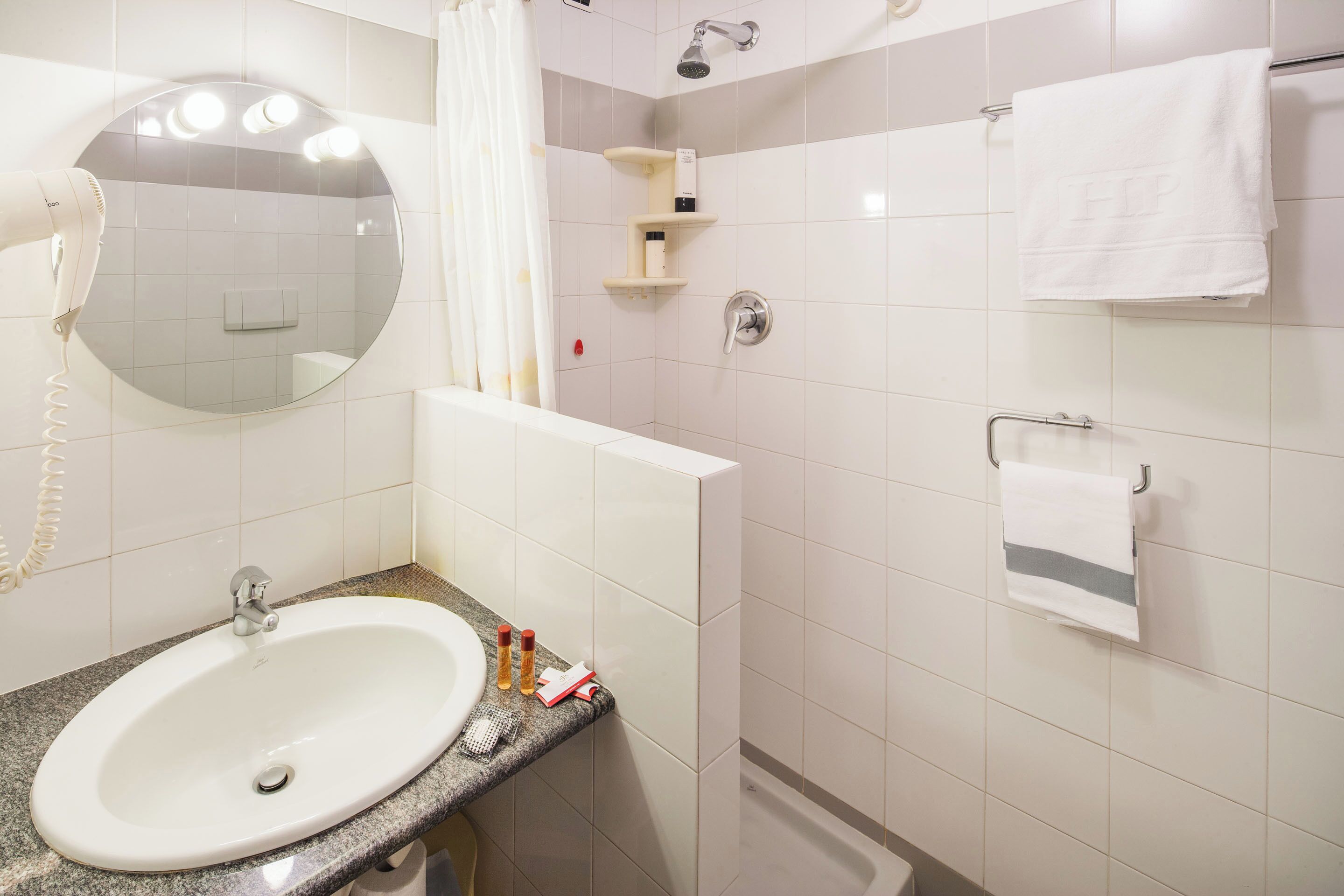 A bathroom with a sink, mirror, towel rack, and shower.