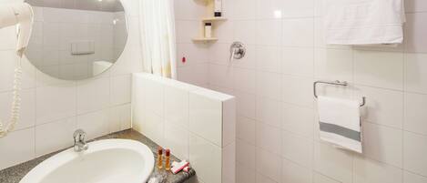 A bathroom with a sink, mirror, towel rack, and shower.