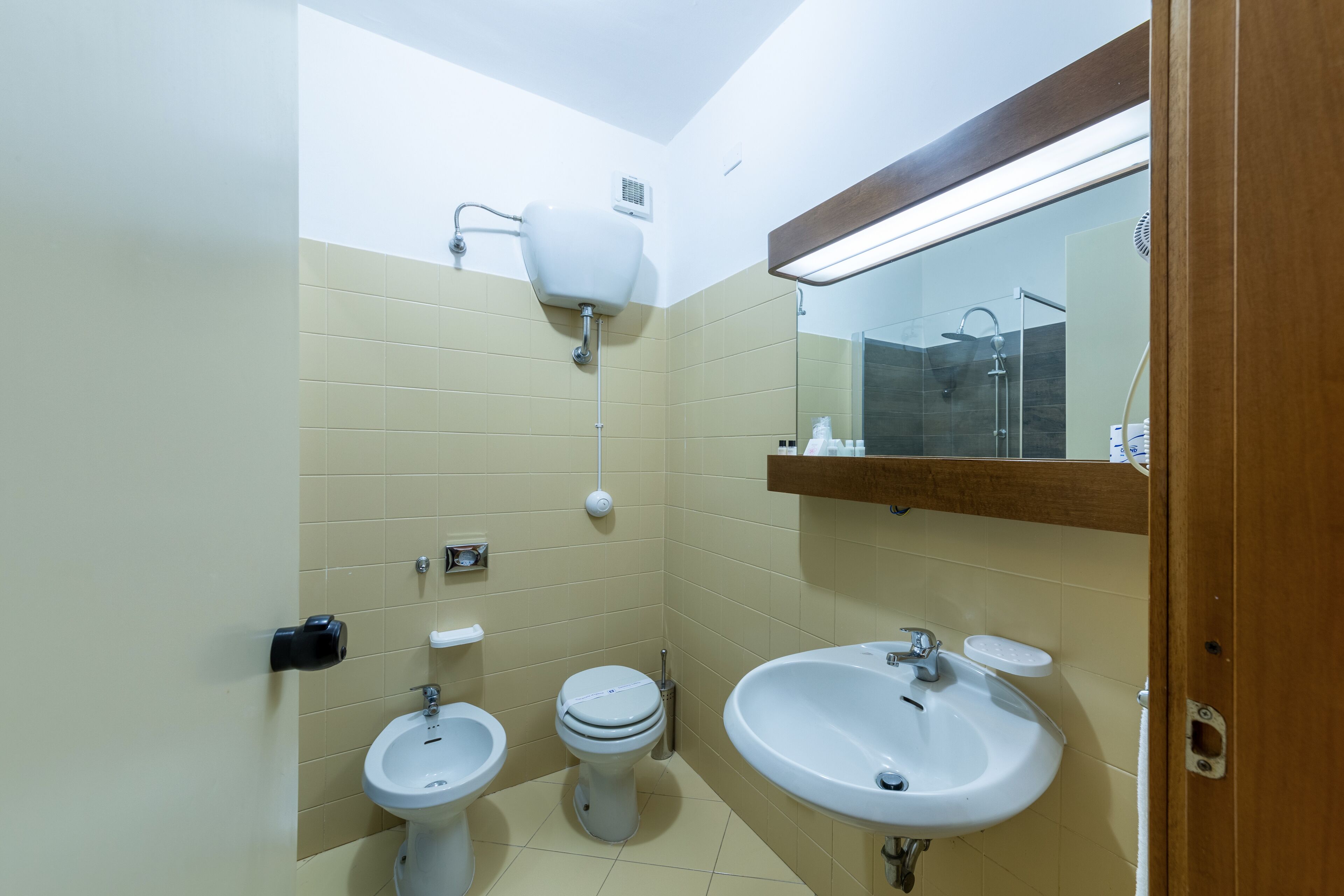 A small, clean bathroom with a toilet, bidet, and sink.