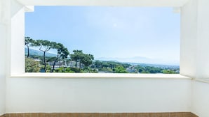 Habitación con vistas a un paisaje urbano, que incluye árboles y montañas a lo lejos.