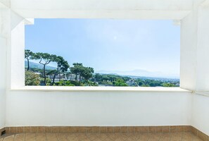 Una habitación con un amplio ventanal que da a una vista panorámica de la ciudad, con árboles y montañas a lo lejos.