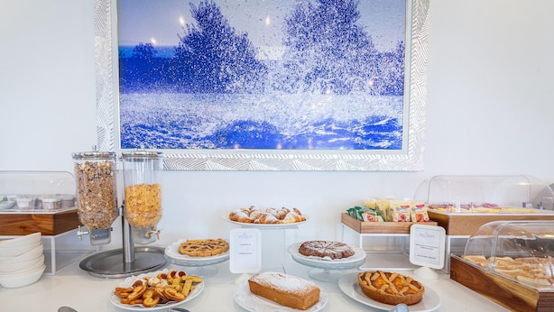 Un bufé con diversas opciones de pastelería y una amplia fotografía enmarcada de un paisaje nevado.