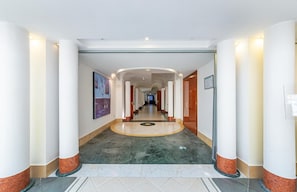 A hotel corridor with marble flooring, white columns, and framed artwork on the walls. - Hotel Sakura, Sure Hotel Collection by Best Western (Torre del Greco)
