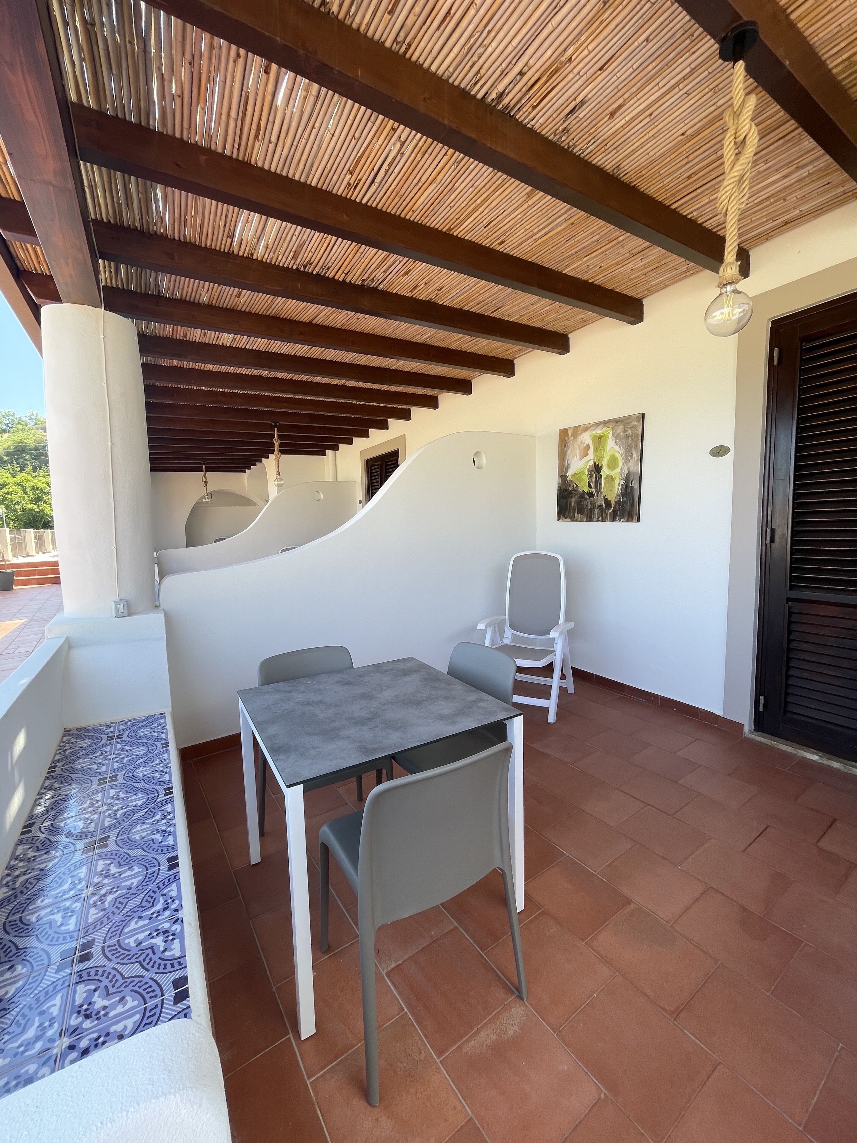 Un patio techado al aire libre con una mesa y sillas, un piso con diseño y un techo de vigas de madera.