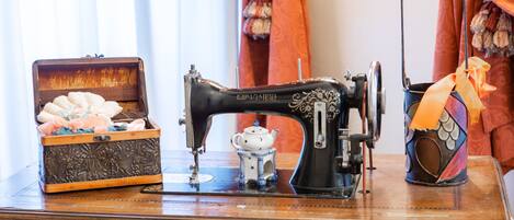A vintage sewing machine on a wooden table with a decorative box and a small teapot.
