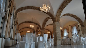 A banquet hall with high arched ceilings, chandeliers, and tables set for a formal event.