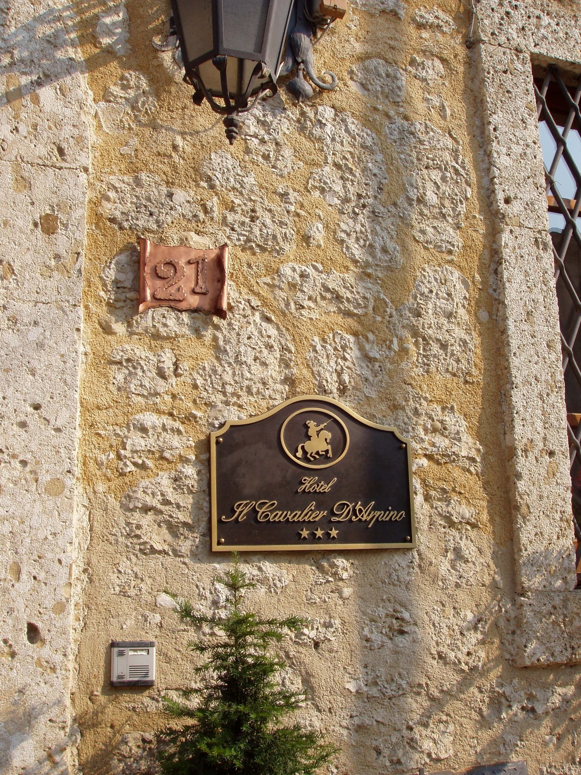A building facade with a sign for "Hotel Il Cavalier D'Aprino" and a number "21" plaque.