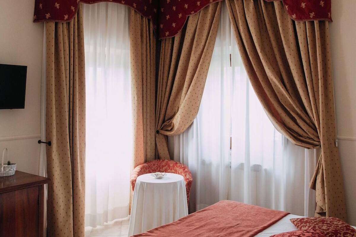 Une chambre d’hôtel avec un lit, une petite table et des rideaux.