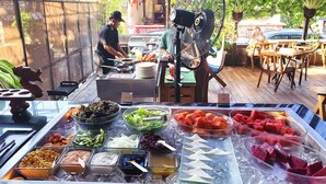 A buffet setup with various food items and a chef preparing food. - Stana Puri Gopa Hotel (Denpasar)