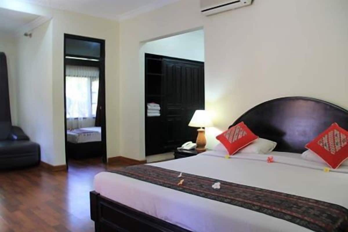 A hotel room with a bed, a nightstand, a lamp, and a wardrobe.