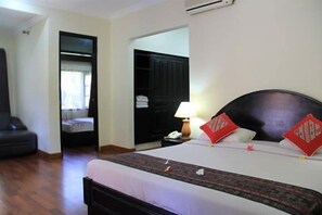 A hotel room with a bed, a nightstand, a lamp, and a wardrobe. - Stana Puri Gopa Hotel (Denpasar)