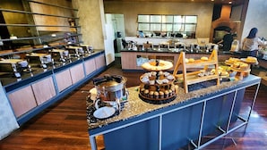 A kitchen area with a buffet setup, including a hot pot station, a variety of pastries, and a display of bread. - Stana Puri Gopa Hotel (Denpasar)