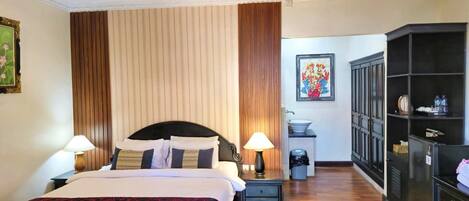 Habitación de hotel con cama, dos mesitas de noche, un armario, lavamanos y un cubo de basura.