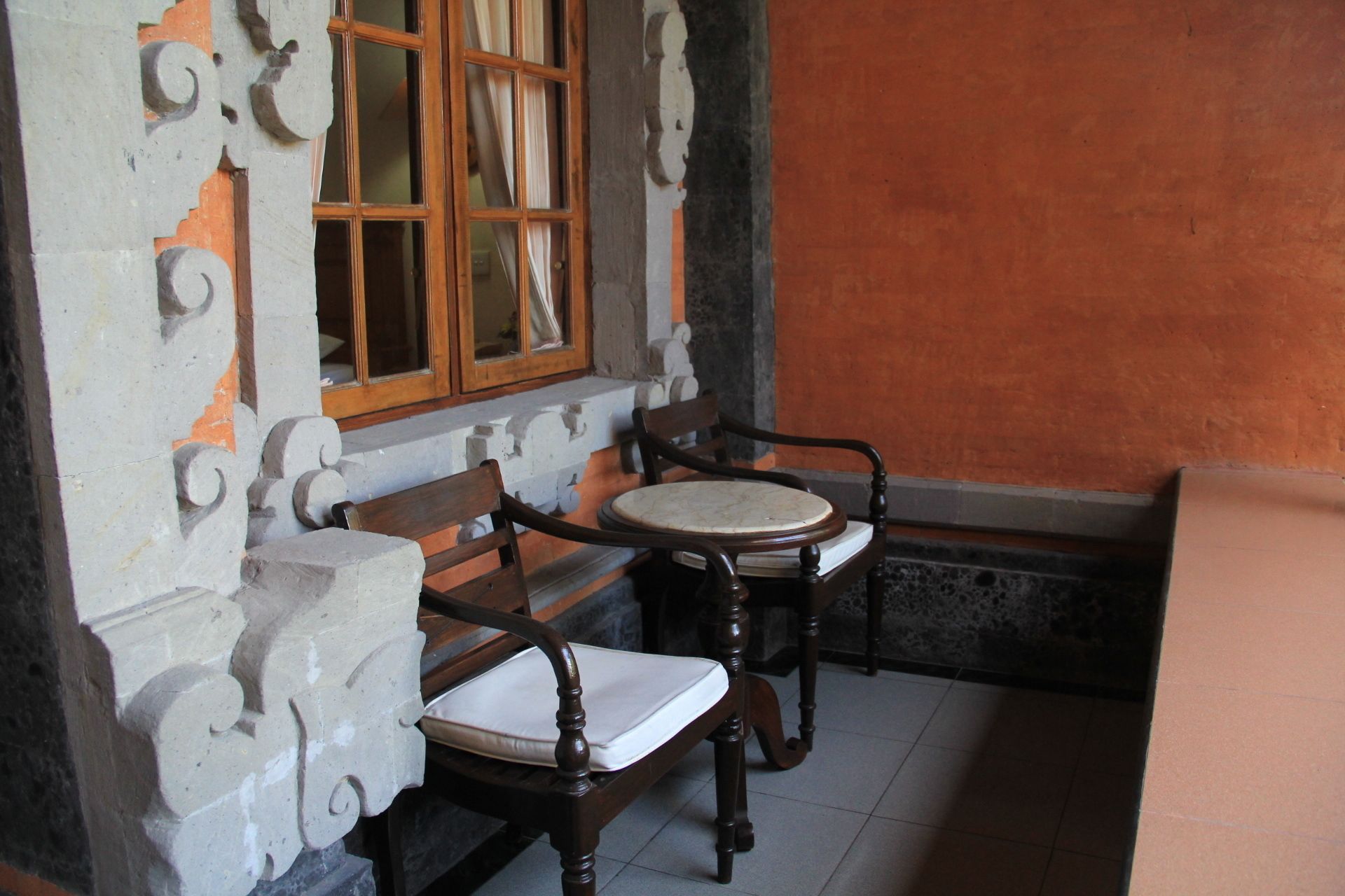 A corner room with two wooden chairs and a window with curtains.