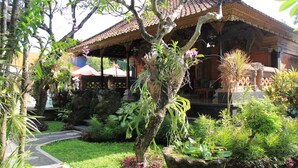 A traditional building with a tiled roof, surrounded by lush greenery and a well-maintained garden. - Stana Puri Gopa Hotel (Denpasar)