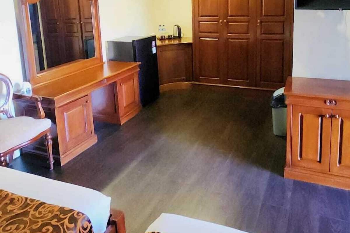 A room with a wooden ceiling, a television, a cabinet, and a table with a patterned tablecloth.