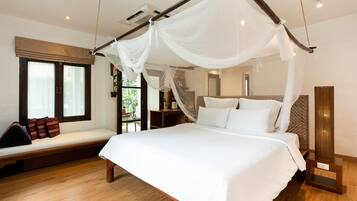 A bedroom with a four-poster bed, a bench with cushions, a bedside table, and a large window.