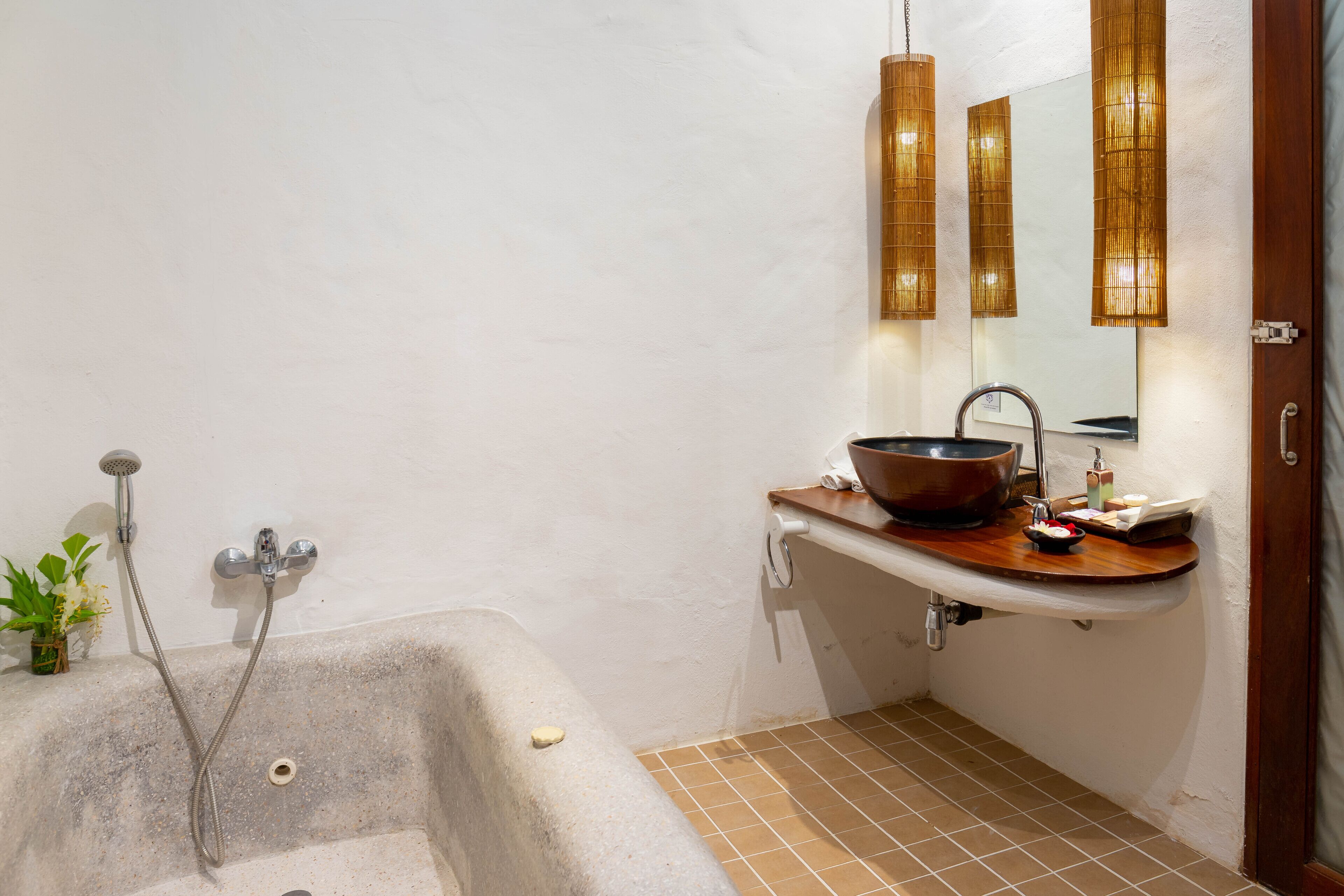 A bathroom with a bathtub, a sink with a large bowl, a mirror, and a showerhead.