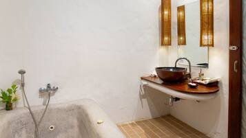 A bathroom with a bathtub, a sink with a large bowl, a mirror, and a showerhead.