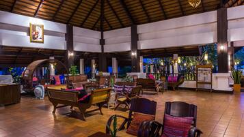 A spacious indoor area with wooden furniture, hanging lights, and a tiled floor.