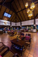 A spacious indoor area with wooden furniture, hanging lights, and a tiled floor.