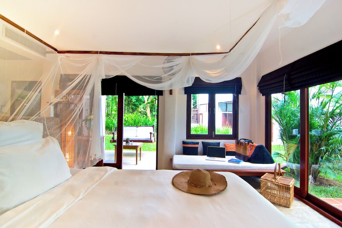 A bedroom with a bed, a window, and a view of greenery.