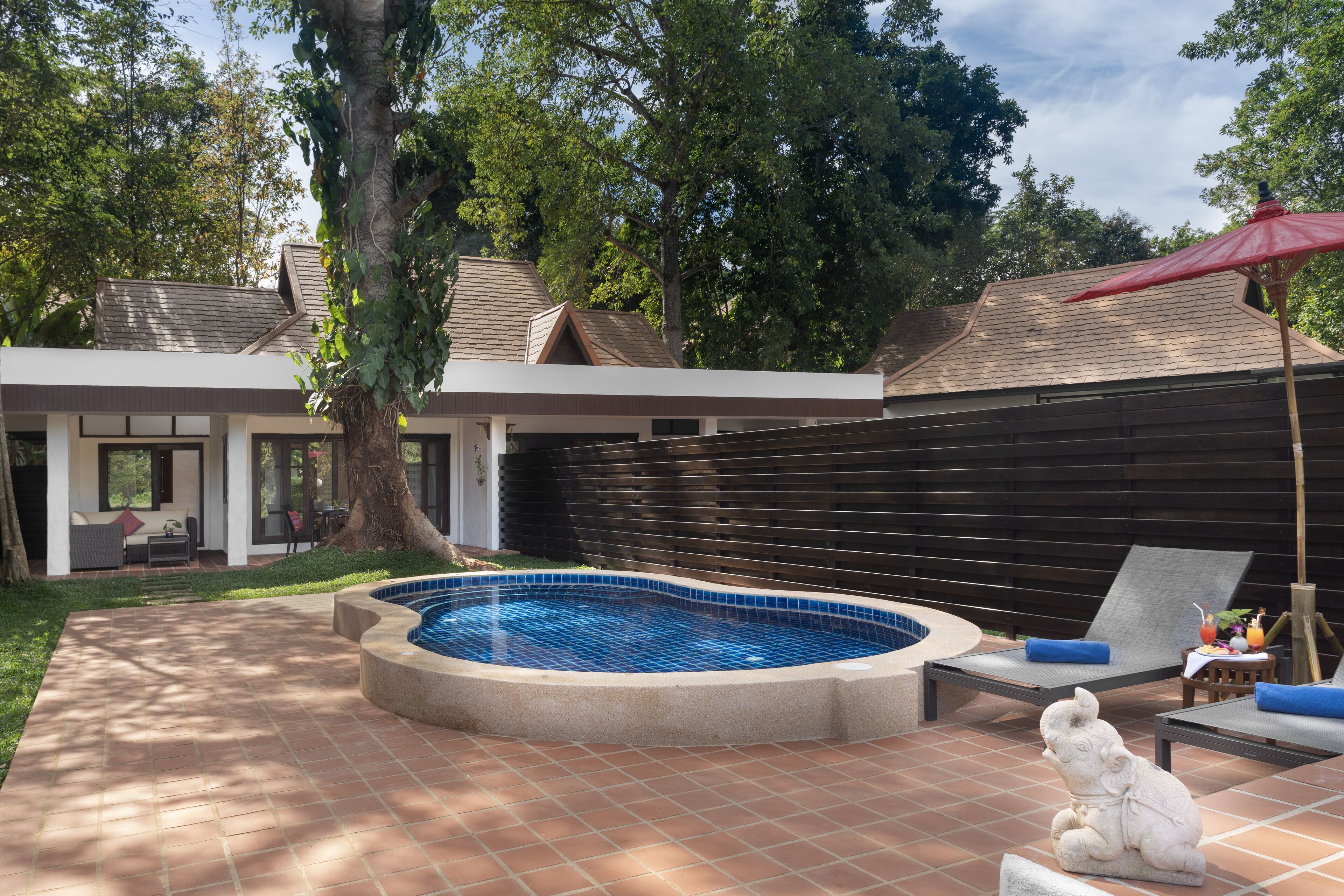 Patio con piscina, sillas de descanso y una estatua.