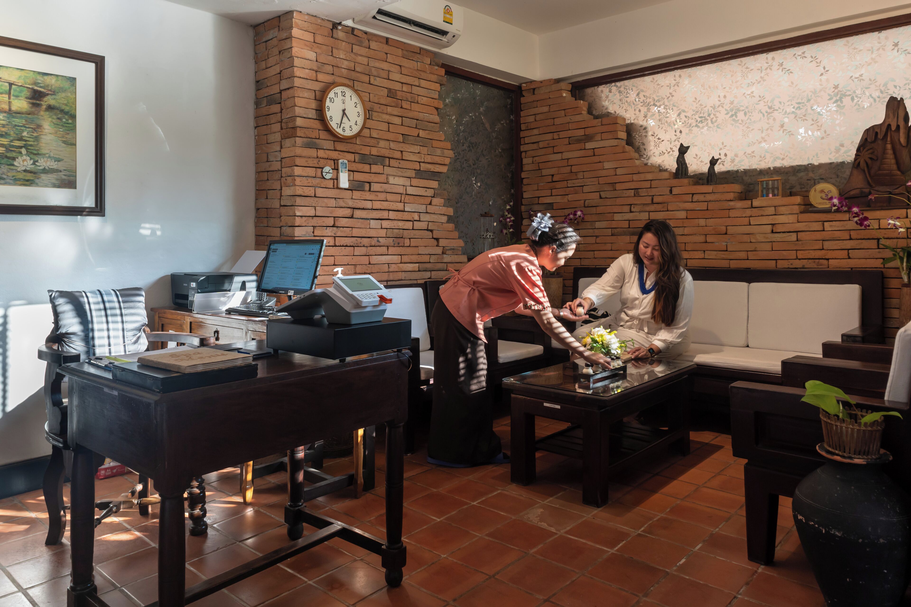 A living room with a brick wall, a clock, a laptop, and a sofa.