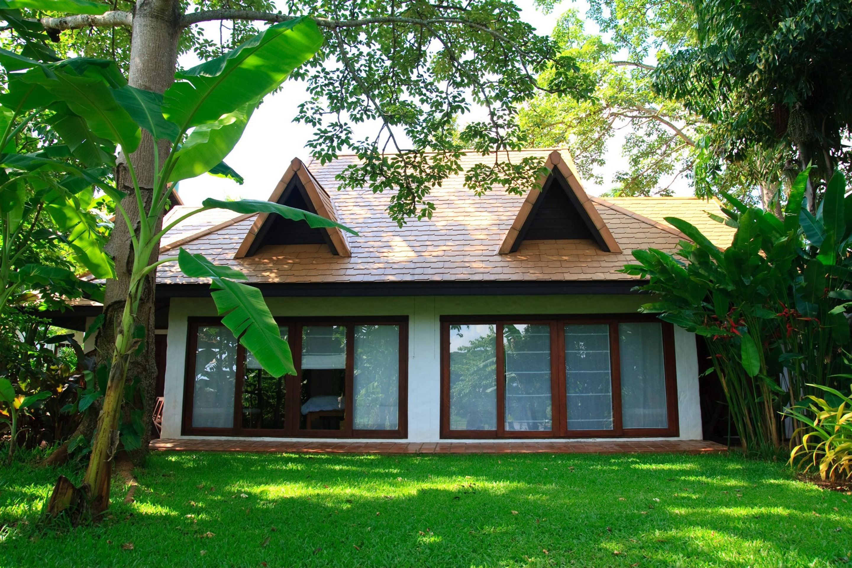 A modern house with a sloped roof, large windows, and a well-maintained lawn.