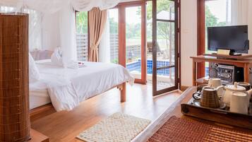 A bedroom with a bed, a TV, a coffee station, and a view of the outdoors.