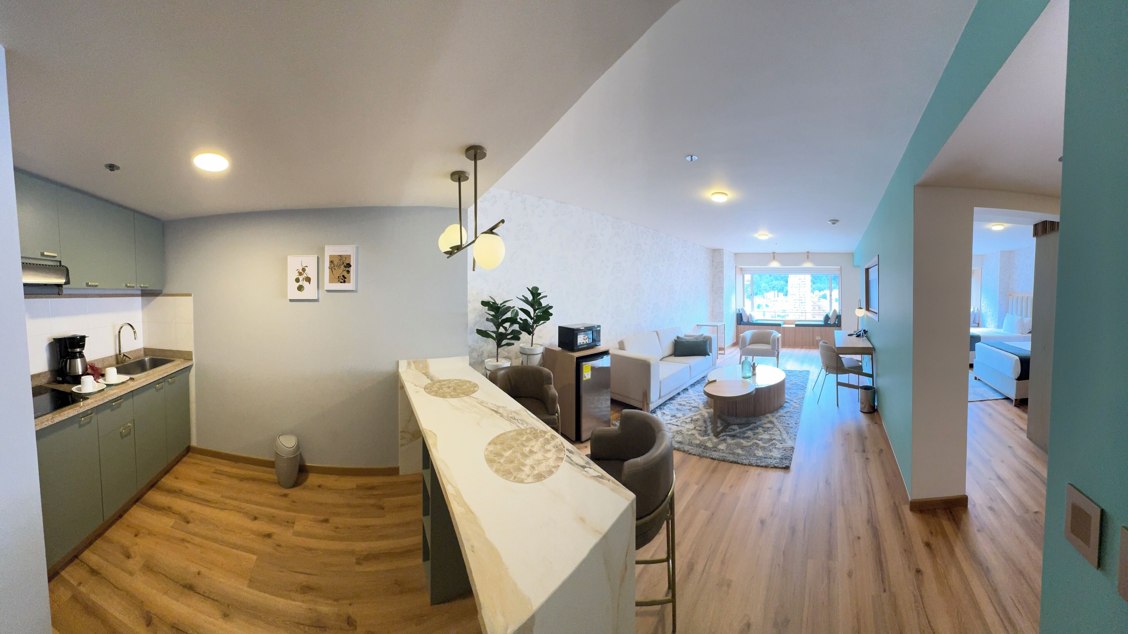 A modern kitchen with a marble countertop, a dining area with a round table, and a living room with a sofa and chairs.