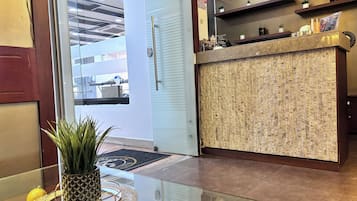 A reception area with a reception desk, a potted plant, and a glass table.