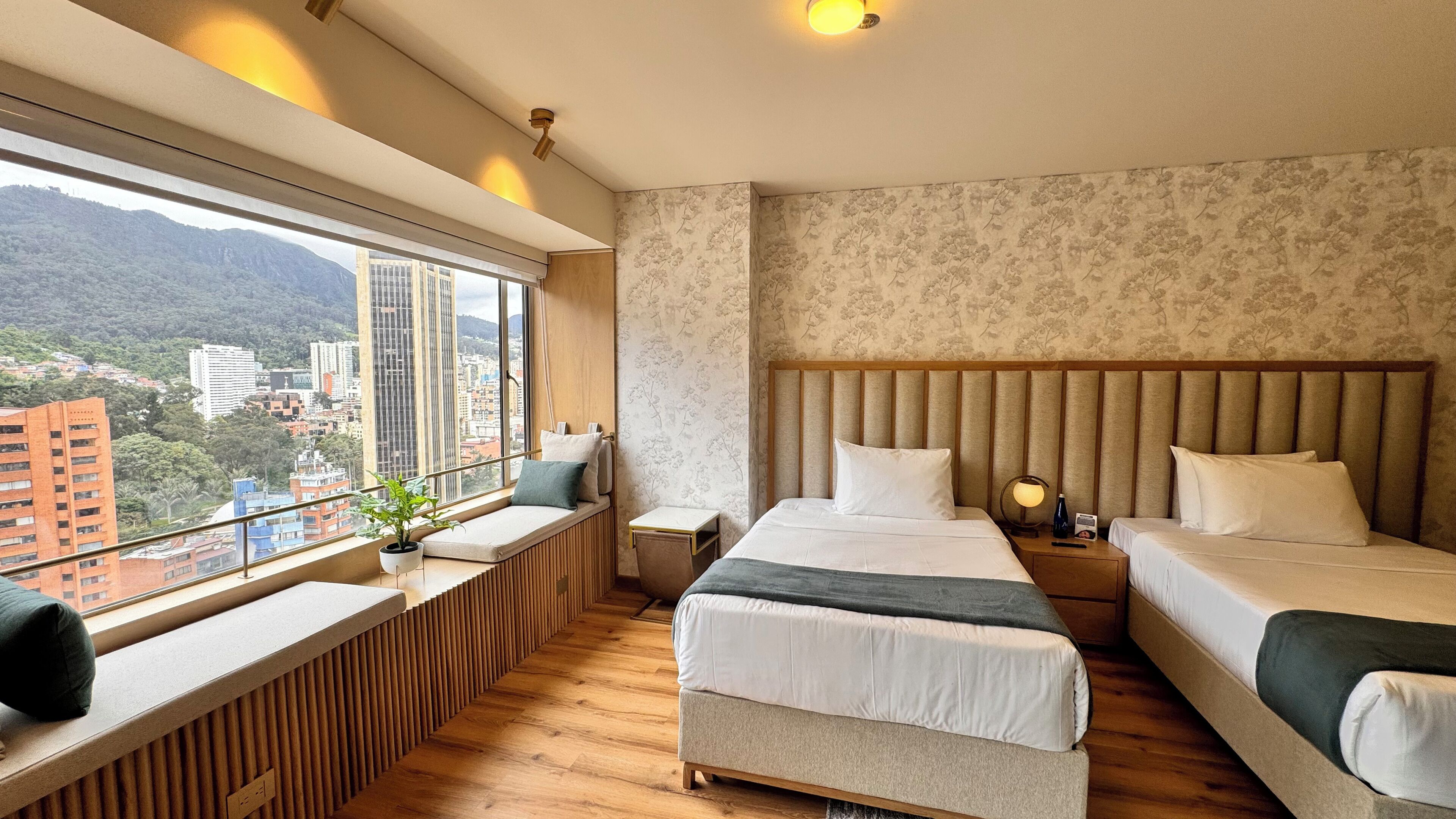 Une chambre d’hôtel avec deux lits, un coin salon près de la fenêtre et une vue sur la ville.