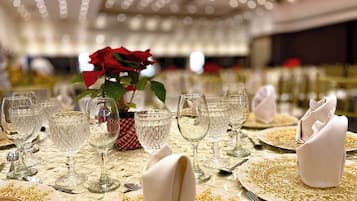 Una mesa de comedor formal adornada con cristalería de cristal, platos con detalles dorados y servilletas blancas.