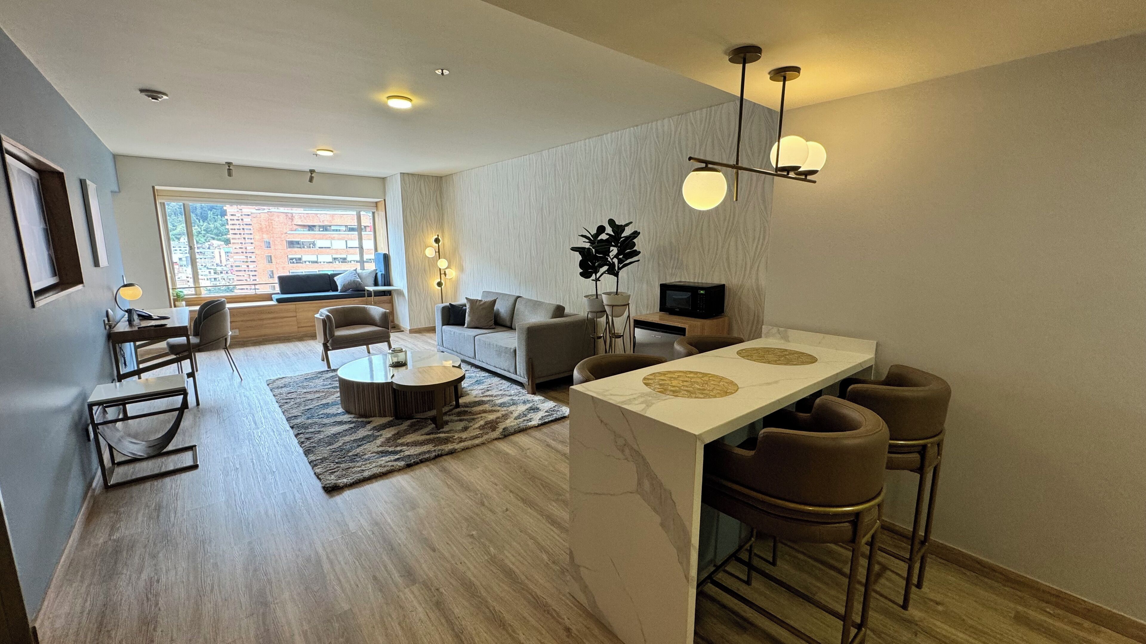 A modern living room with a sofa, coffee table, and a dining area with bar stools.