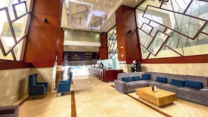 A spacious lobby with a modern design, featuring a large seating area with sofas and armchairs, a reception desk, and a staircase leading to upper levels. -  Tequendama Suites Bogota (Bogotá)