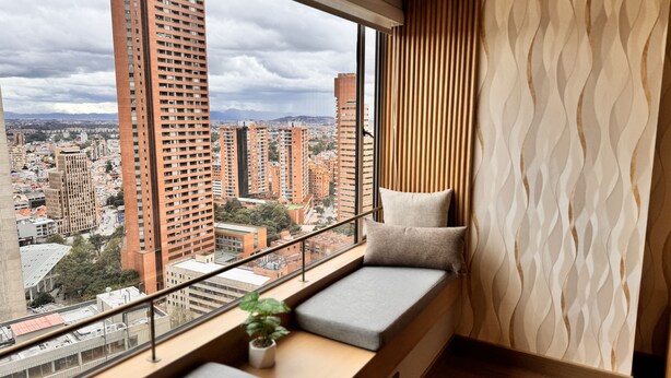A high-rise apartment with a large window, a cushioned bench, and a potted plant. -  Tequendama Suites Bogota (Bogotá)