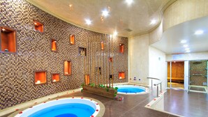 A spa area with two hot tubs, a mosaic wall, and a wooden bench. -  Tequendama Suites Bogota (Bogotá)