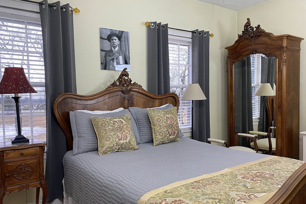 A bedroom with a wooden bed, two bedside lamps, a large mirror, and a picture on the wall.