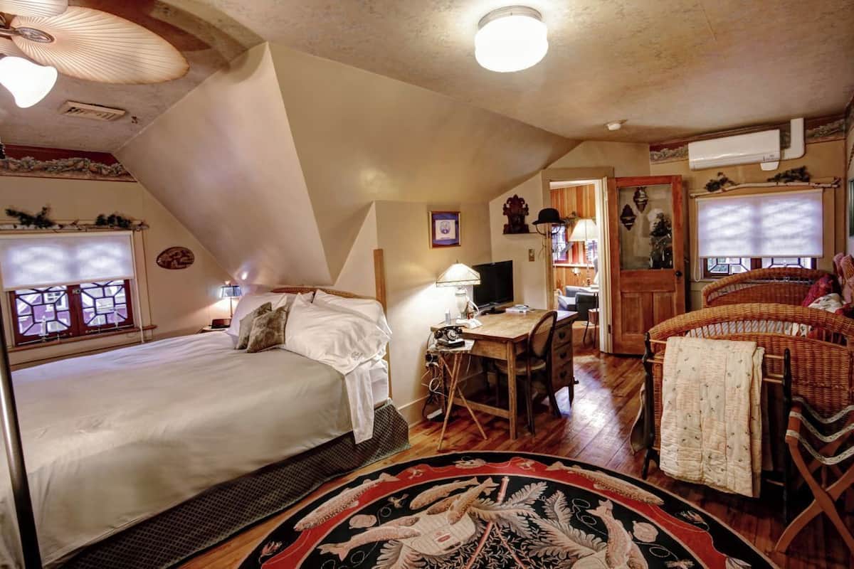 Une pièce confortable avec un lit, un bureau et un fauteuil en osier.