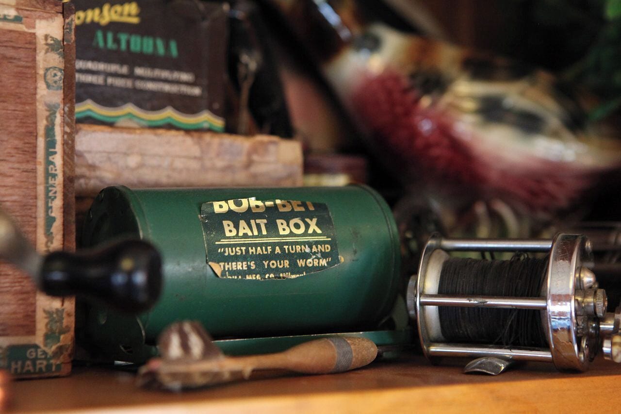 A green bait box labeled "BUB-BET Bait Box" with a slogan, a spool of fishing line, and a wooden box with text.